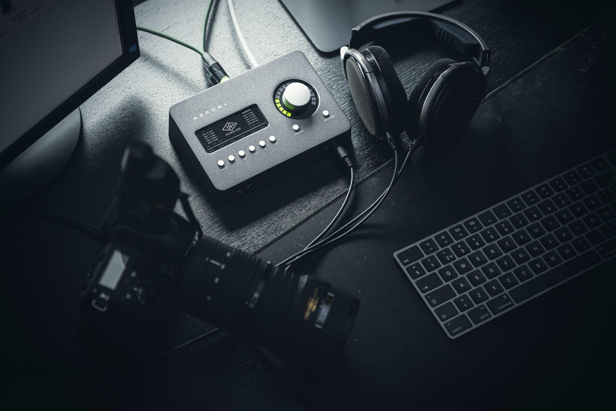 Markkinoinnin työkalut pöydällä. Kamera, tietokone, näppäimistö, kuulokkeet ja äänikortti.